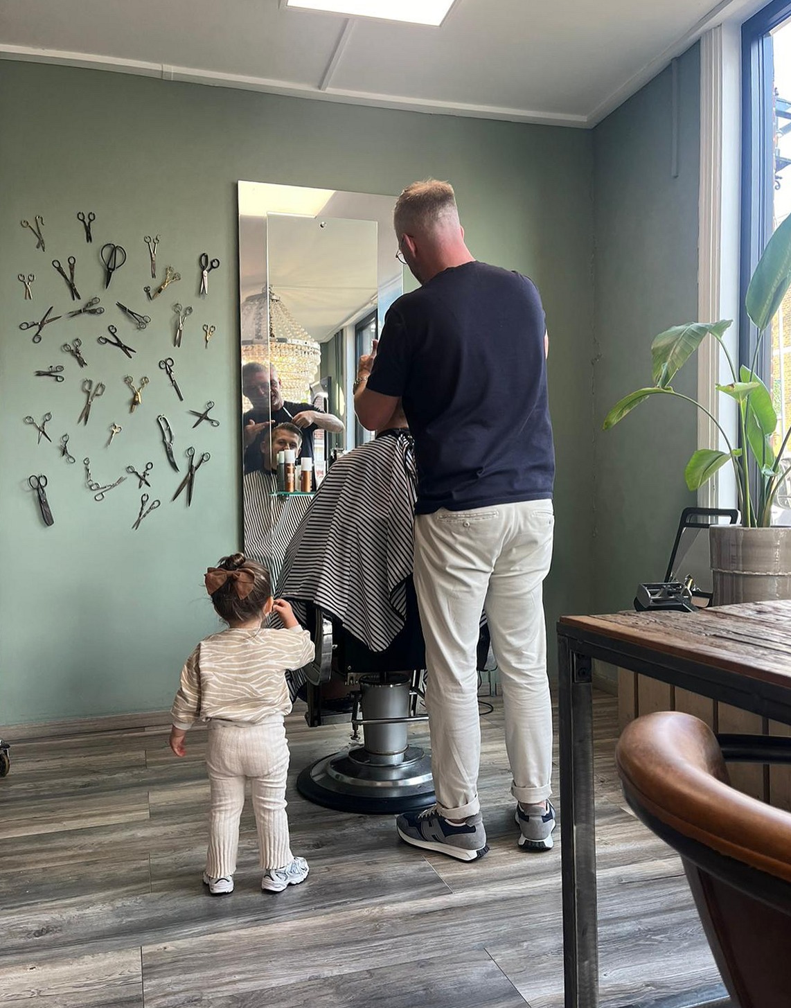 Aan het werk in de salon, voor de wand met oude scharen